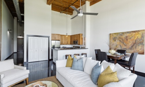 Contemporary open-layout interior showcasing a white sofa, minimalist dining setup, and a modern kitchen with wood cabinetry and tall ceilings, creating a warm, welcoming atmosphere; keywords: 2 bedroom apartments Greenville SC, apartments for rent Greenv